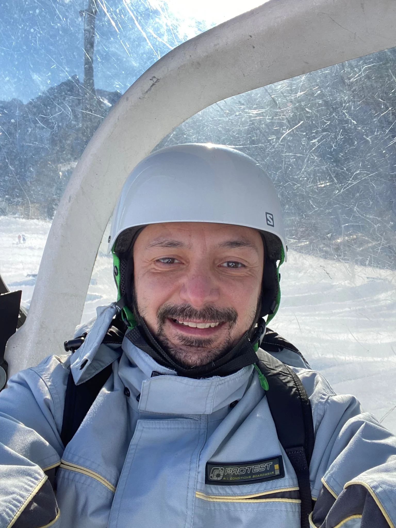 un uomo che indossa un casco e occhiali e sorride alla telecamera